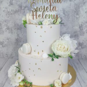 Tort komunijny dwupiętrowy z białymi kwiatami i złotym topperem